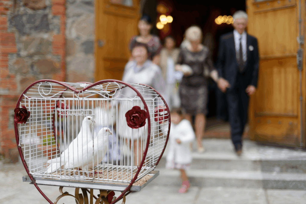 Zwei weiße Tauben sind in einem herzförmigen Käfig bei kirchlicher Trauung