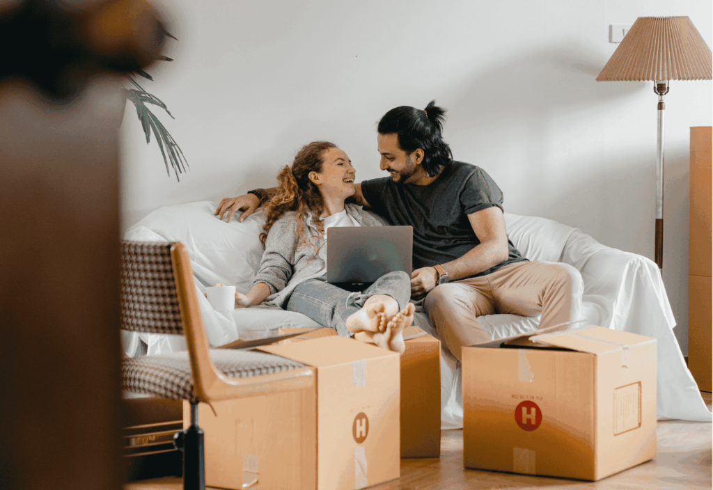 Ein Paar sitzt eng beieinander auf dem Sofa und schaut gemeinsam ihr Hochzeitsvideo und Fotos an.