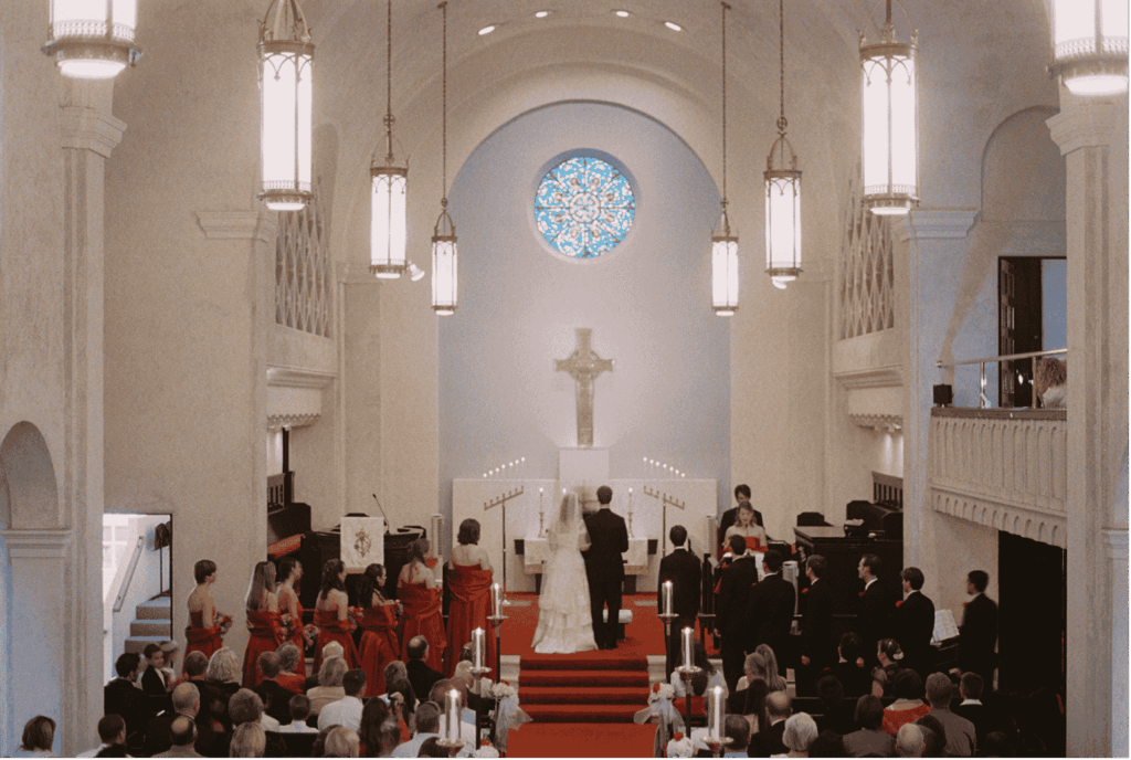 Ein Brautpaar in eleganter Hochzeitskleidung steht vor dem Altar einer prächtigen Kirche. Im Vordergrund sind die Trauzeugen und die Gäste zu sehen, die an der Zeremonie teilnehmen.
