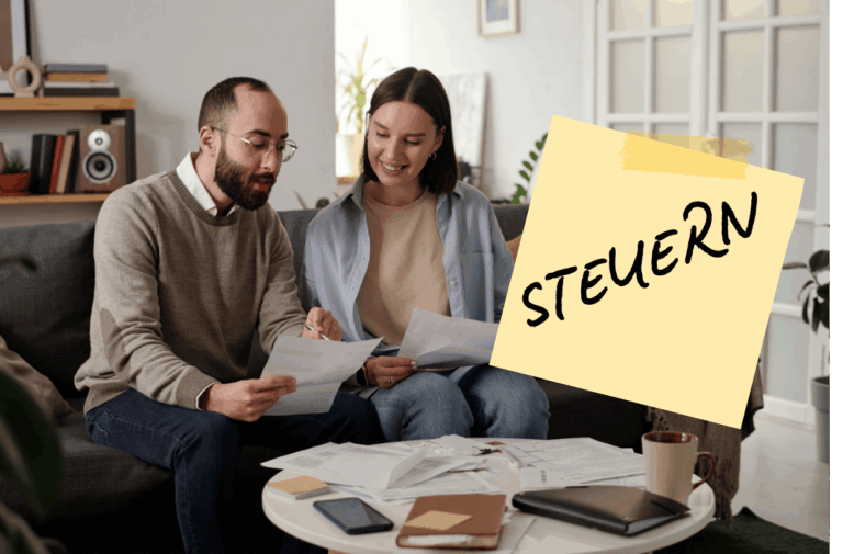 Ein glückliches Ehepaar sitzt auf einem Sofa und bespricht Dokumente, mit Notizen und Unterlagen auf dem Tisch, während ein Post-it mit dem Wort "STEUERN" (Steuern) prominent im Vordergrund ist.