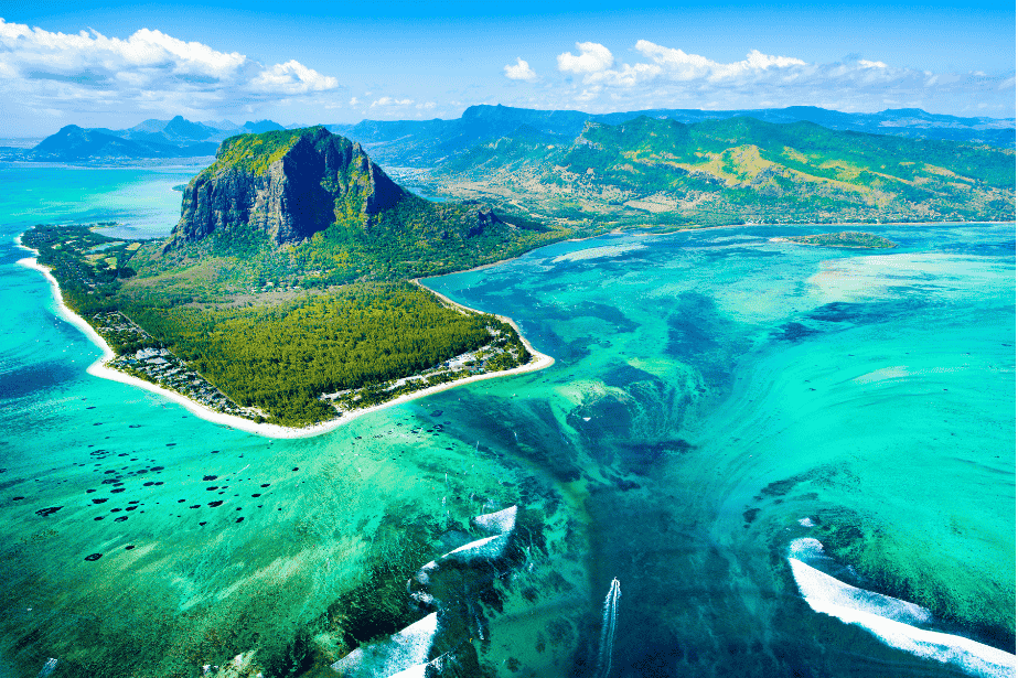 Atemberaubende Luftaufnahme der Halbinsel Le Morne Brabant auf Mauritius, umgeben von türkisfarbenem Wasser, das durch Sandbewegungen wie ein Unterwasser-Wasserfall aussieht.